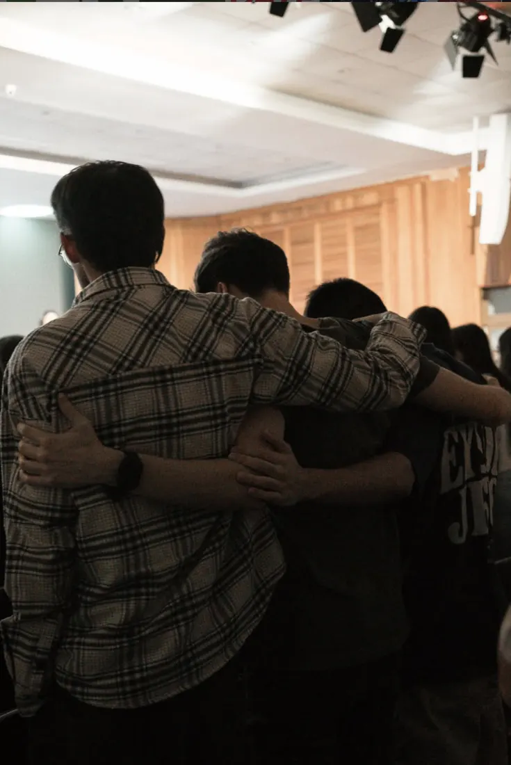 Jovens abraçados orando juntos durante o culto
